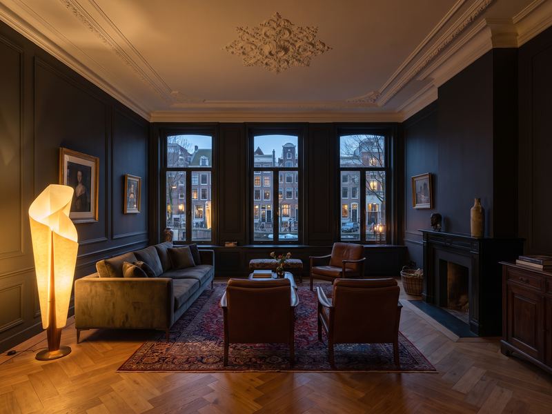 Gerenoveerde woonkamer in een Amsterdams grachtenpand met visgraatvloer en donker paneelwerk